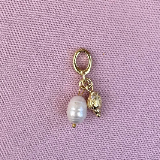 Gold charm with a pearl on a pink background
