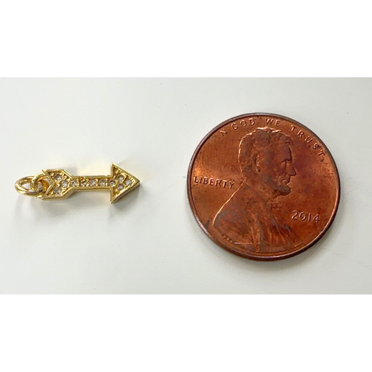 Gold arrow pendant next to a penny on a white background