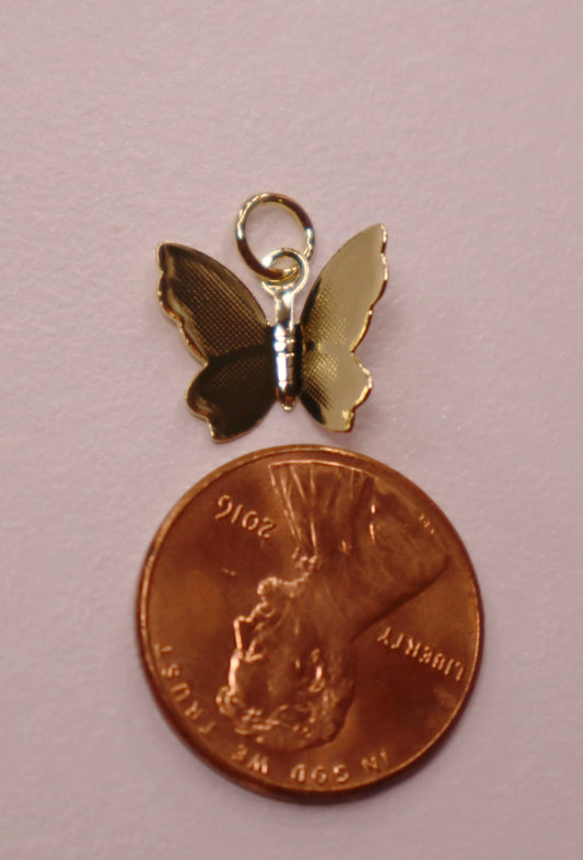 Butterfly charm on a penny against a pink background