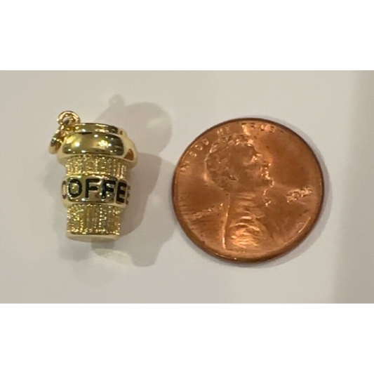 Gold coffee cup charm next to a penny on a white background
