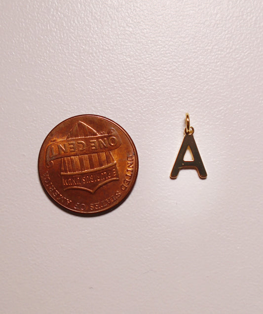Copper coin and gold letter 'A' charm on a white background
