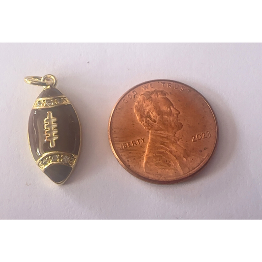 Gold football-shaped pendant next to a penny on a white background