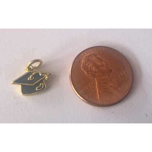Gold graduation cap charm next to a penny on a white background
