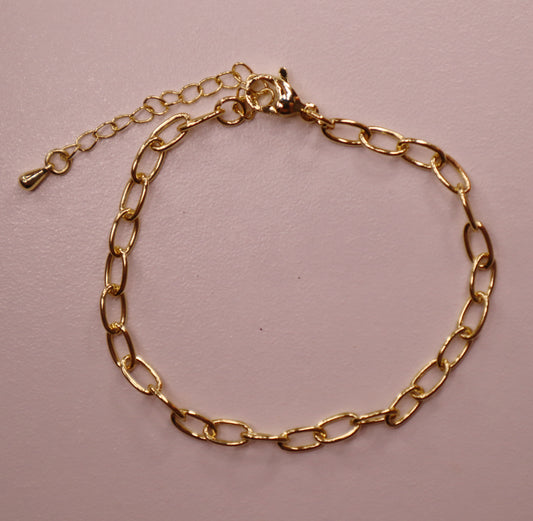 Gold oval chain bracelet on a pink background