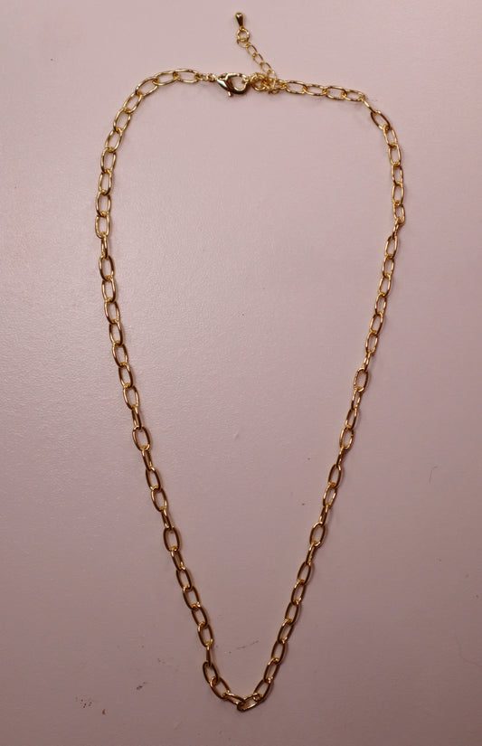 Gold oval necklace on a light pink background