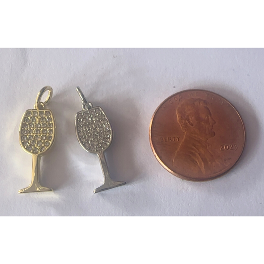 Two gold wine glass-shaped pendants next to a penny on a white background
