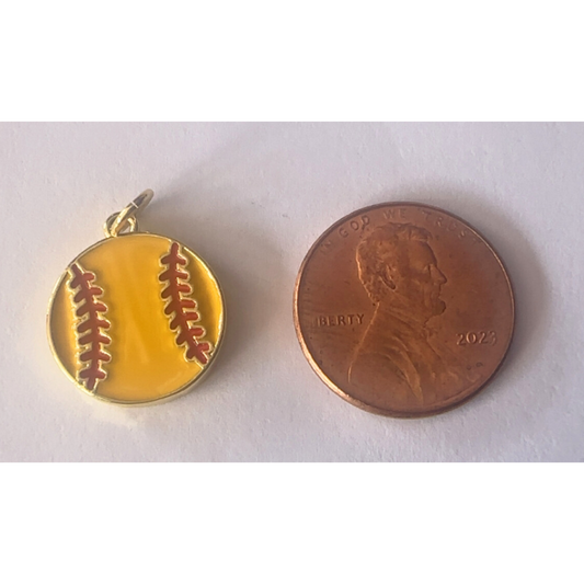 Gold softball pendant next to a penny on a white background