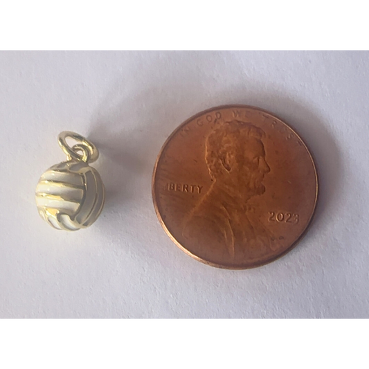 Gold volleyball charm next to a penny on a white background
