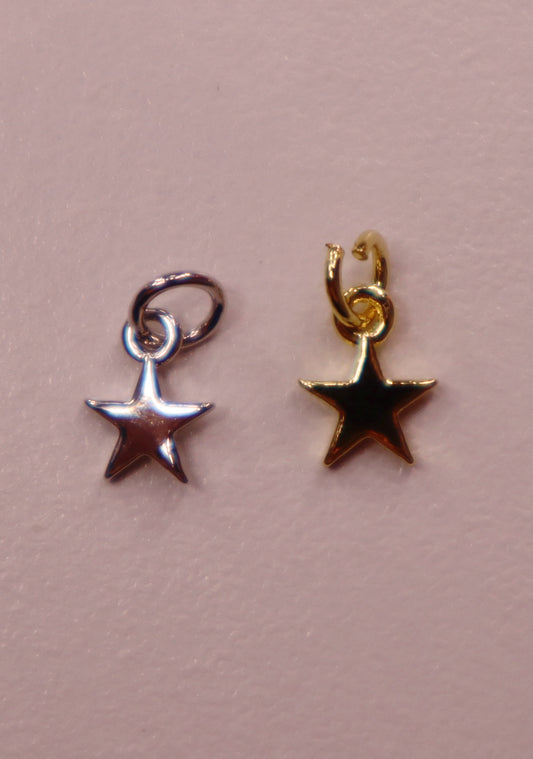 Two star-shaped charms, one silver and one gold, on a pink background.
