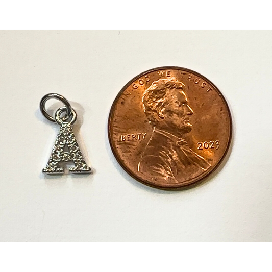 Silver letter 'A' charm next to a penny on a white background