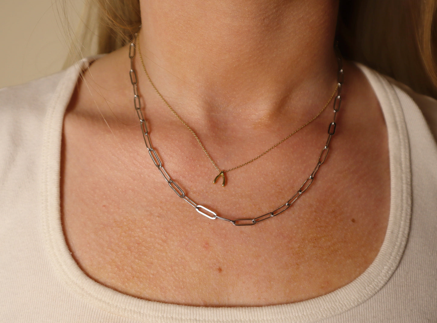 paperclip silver Necklace with a small pendant on a person wearing a beige top.