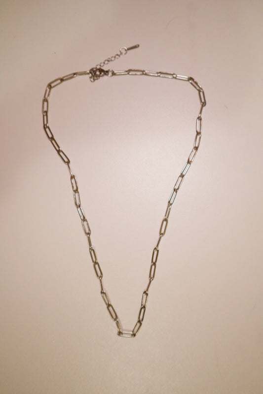 Silver paperclip chain necklace on a beige background