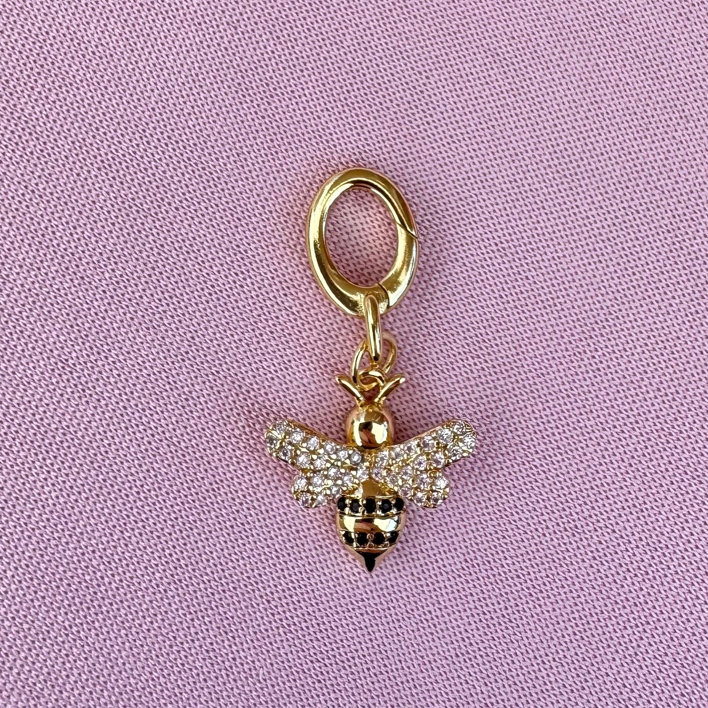Gold bee bikini charm on a pink background