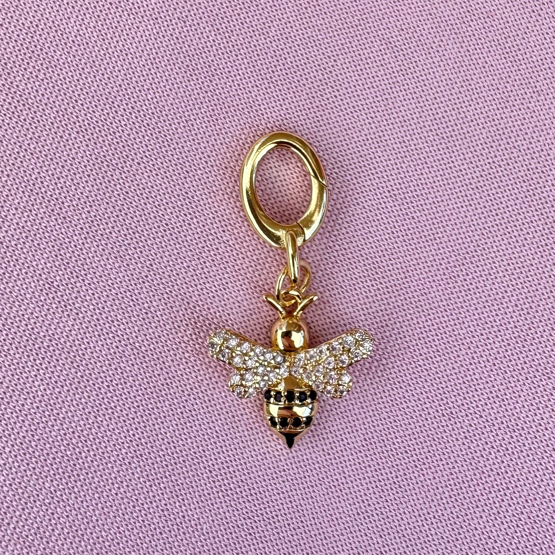 Gold bee bikini charm on a pink background