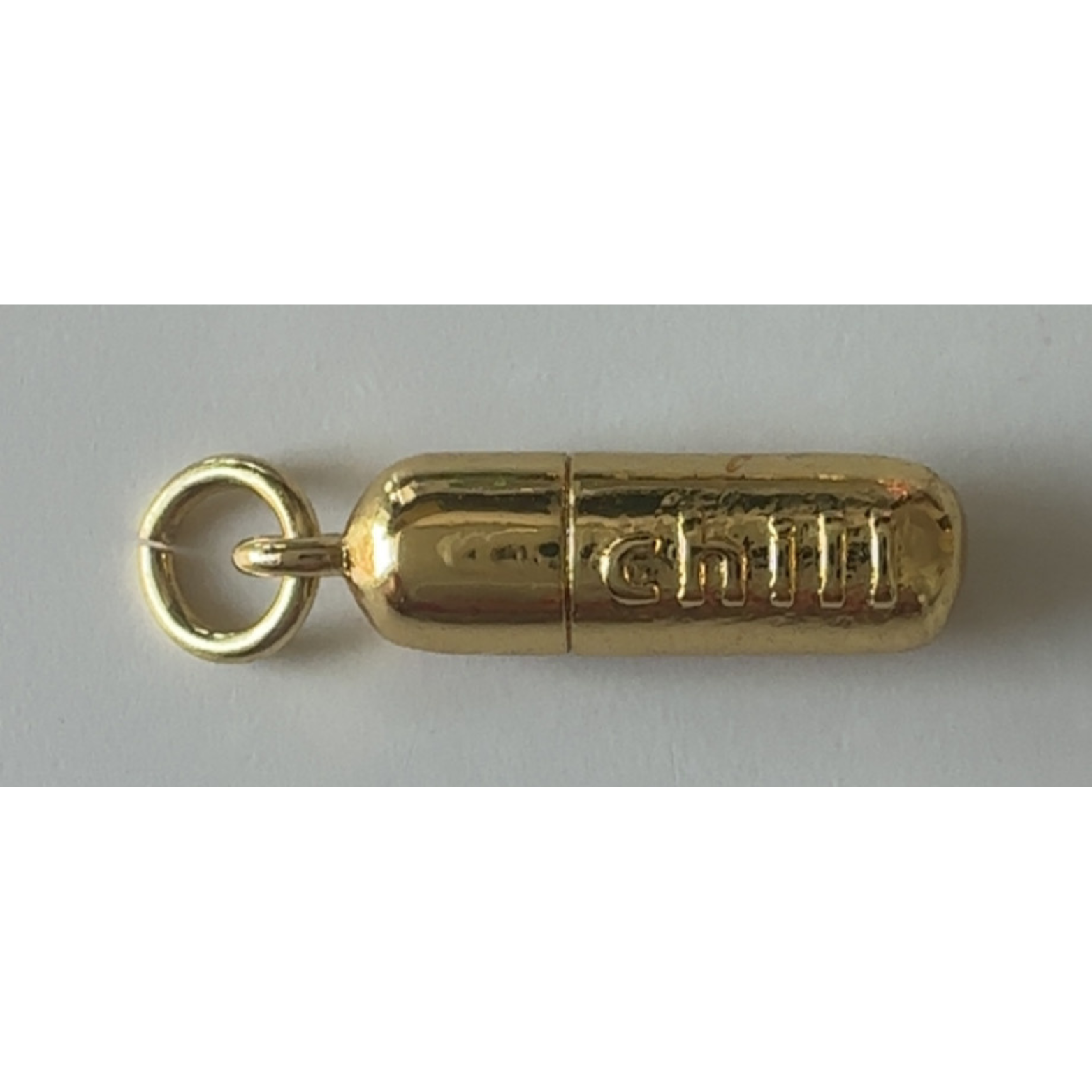 Gold cylindrical charm with 'Chili' branding on a gray background
