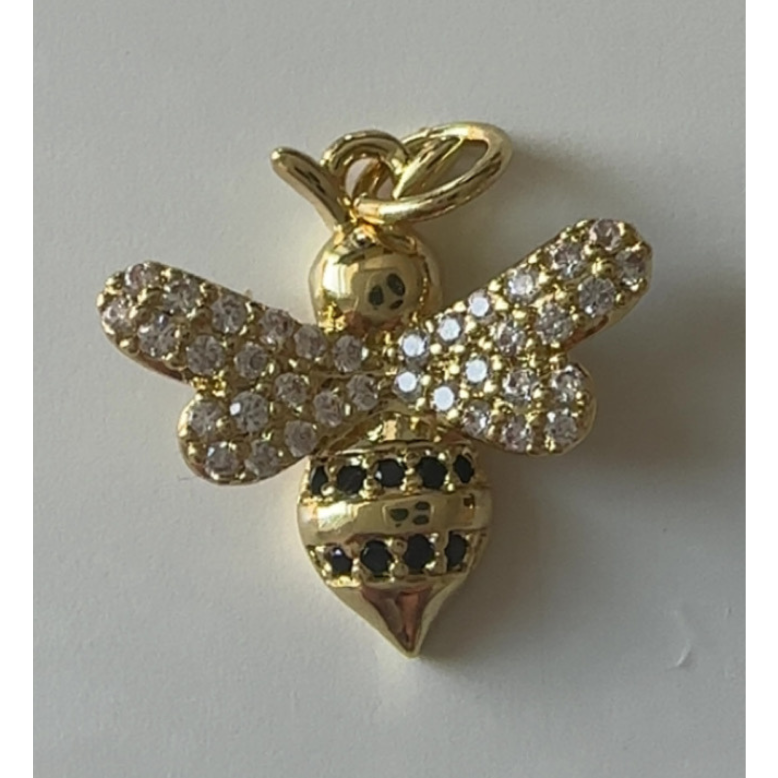 Gold bee pendant with gemstones on a white background