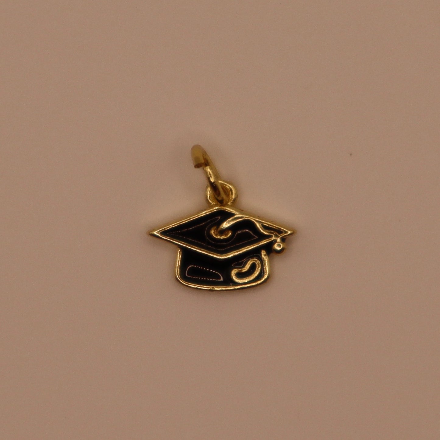 Gold and black graduation cap pendant on a beige background