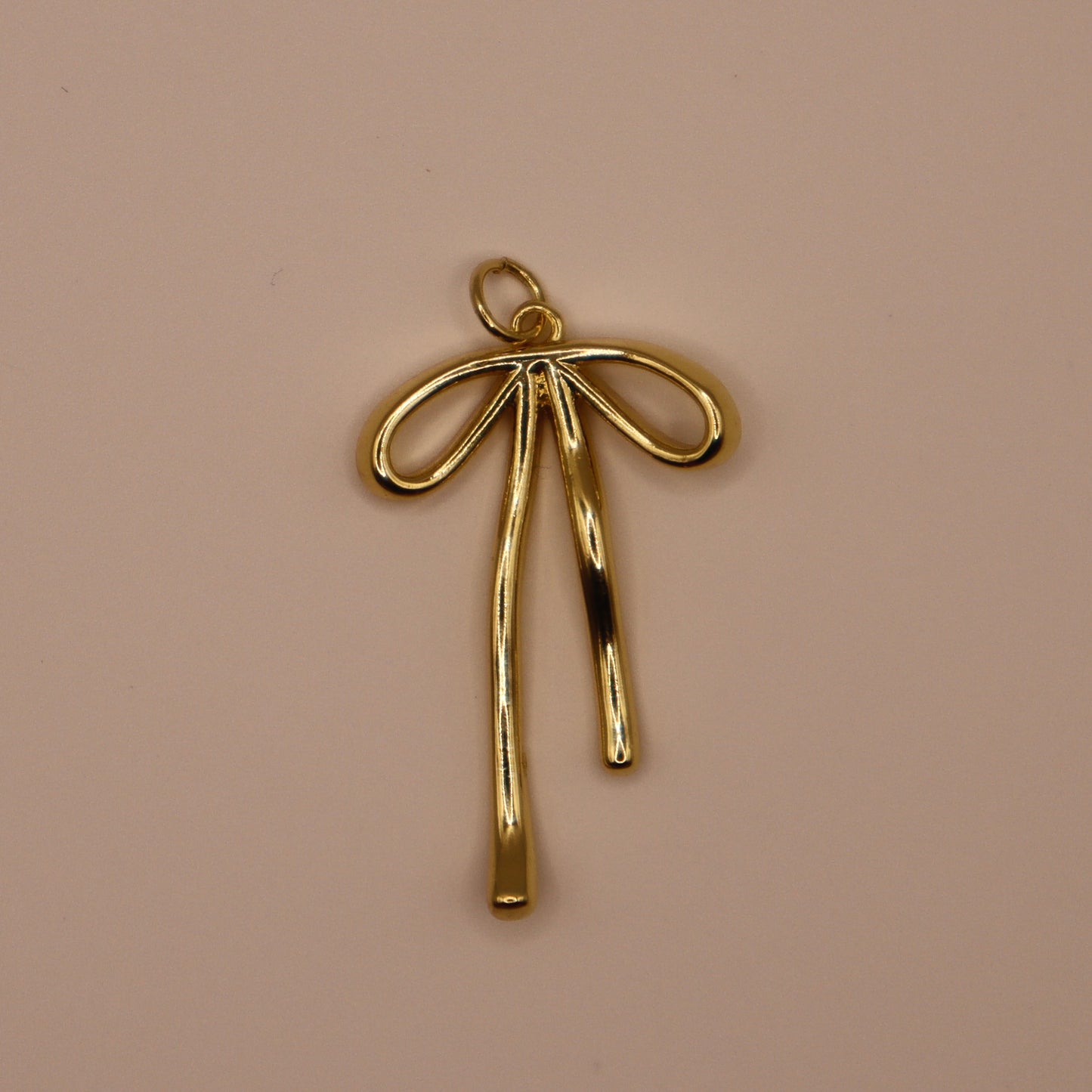 Gold bow-shaped pendant on a beige background