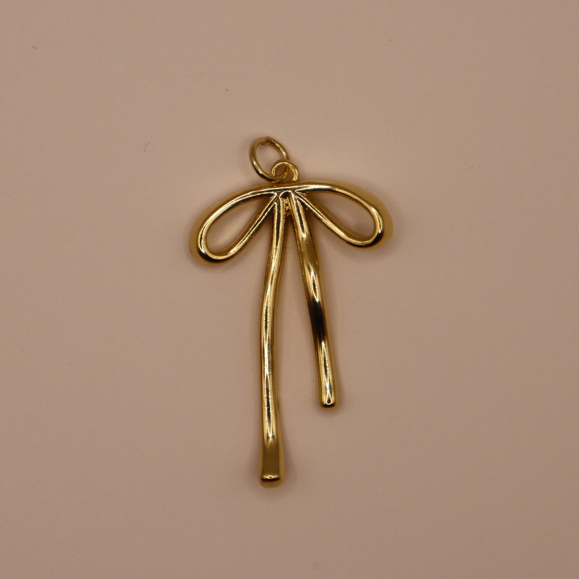 Gold bow-shaped pendant on a beige background