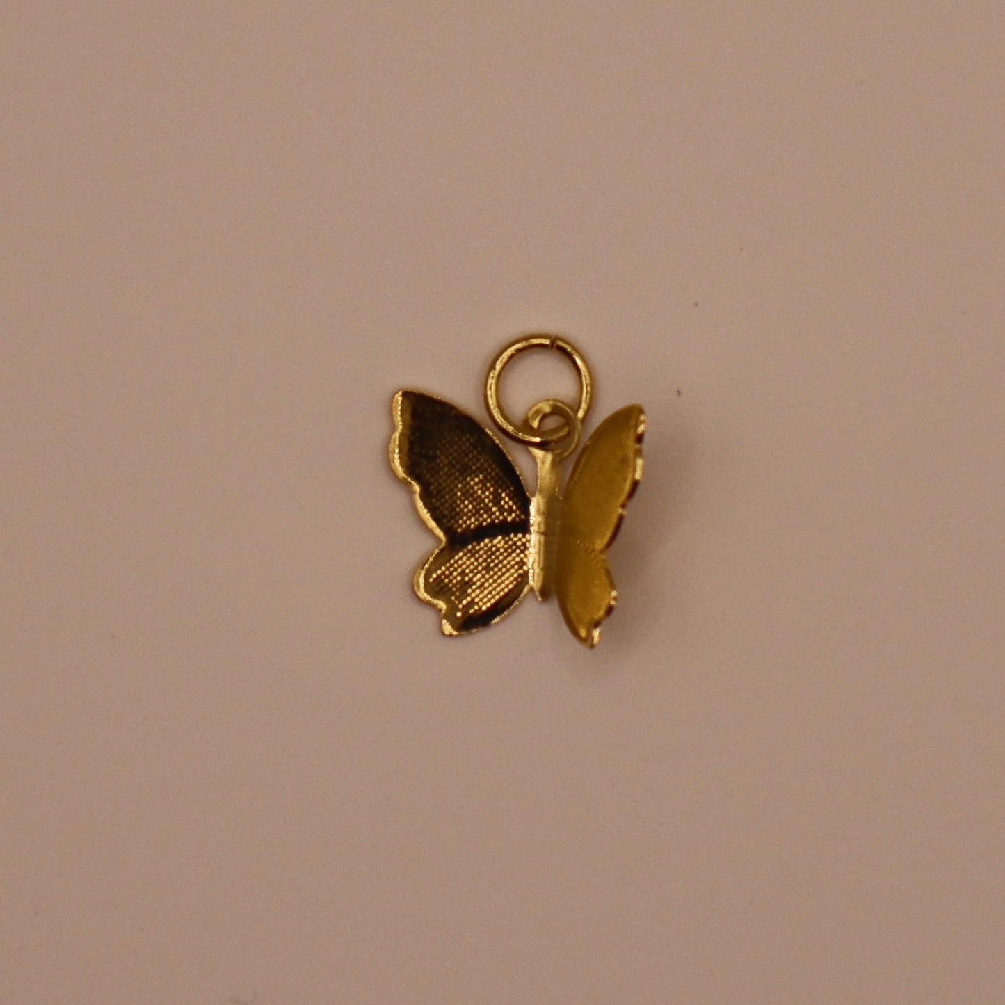 Gold butterfly charm on a beige background