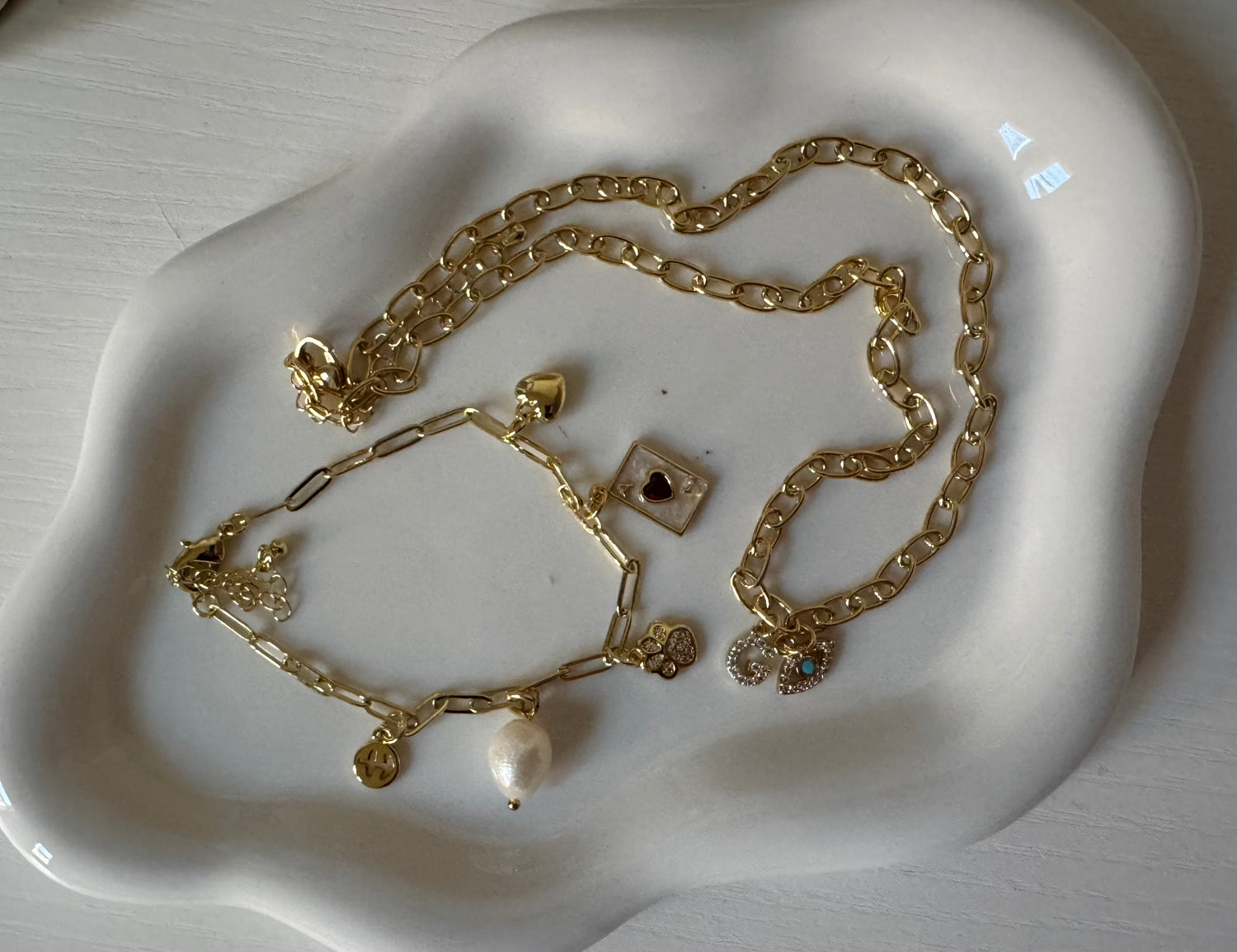 Gold jewelry set including necklace, bracelet, and earrings on a white dish.