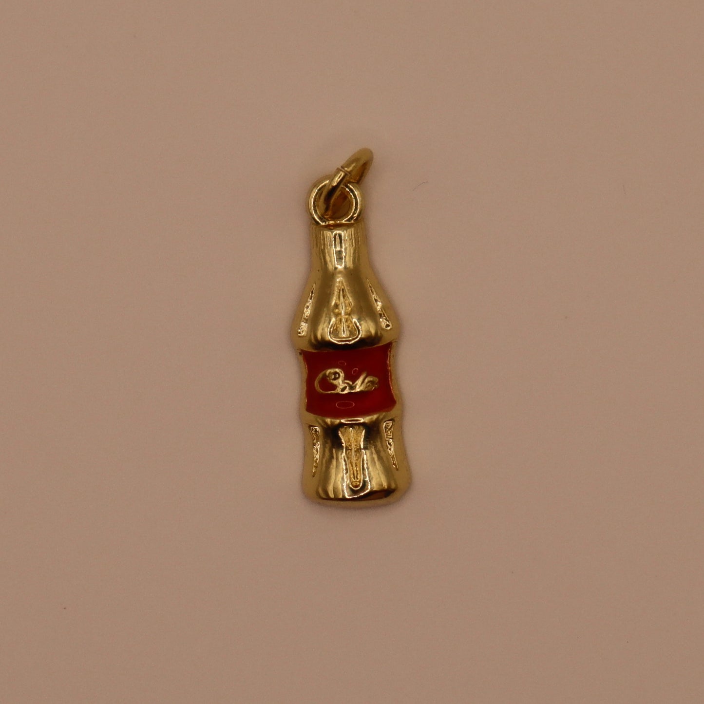 Gold Coca-Cola bottle charm on a beige background