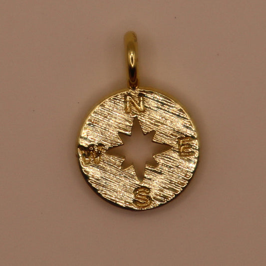 Gold compass charm on a brown background