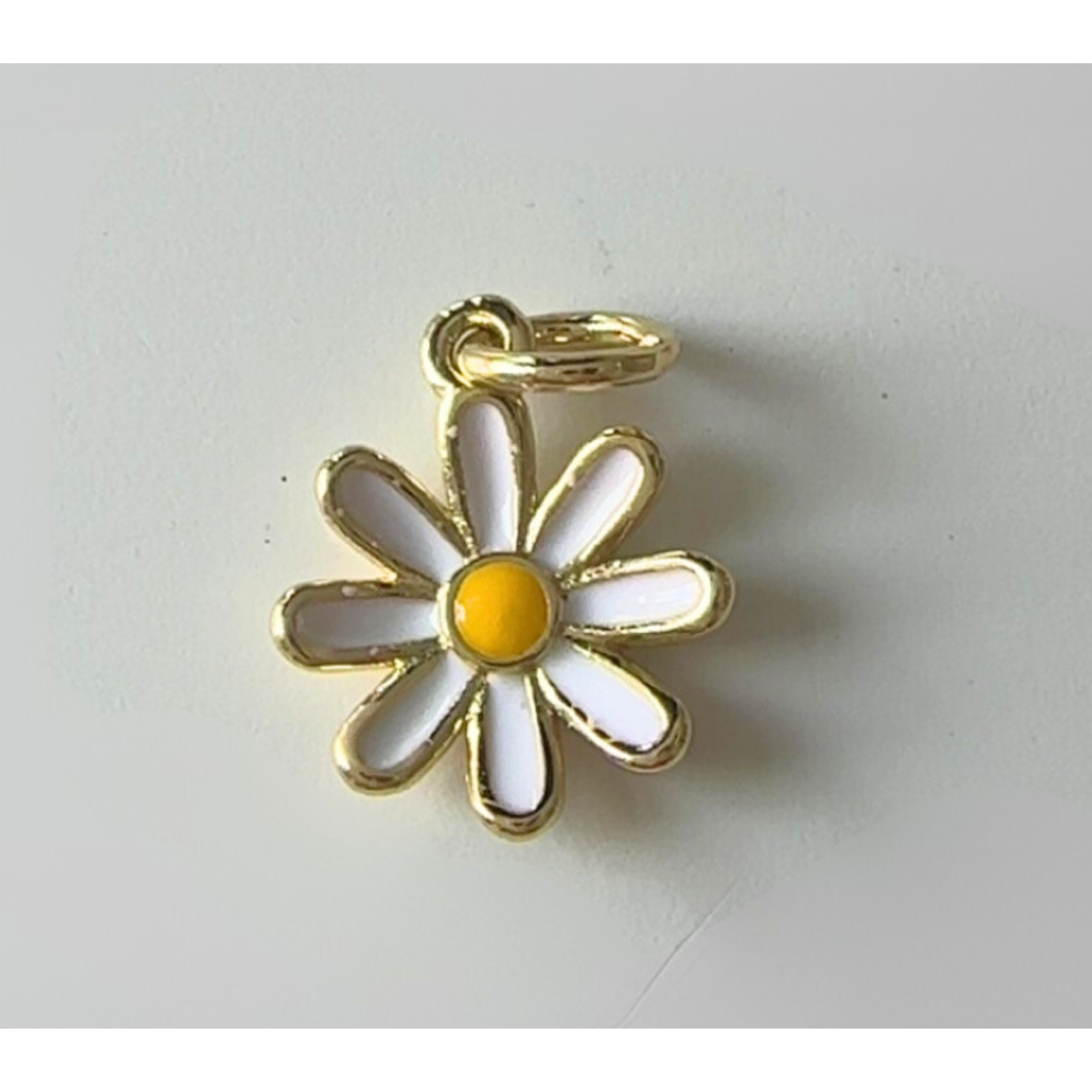 Daisy-shaped pendant with gold outline on a white background