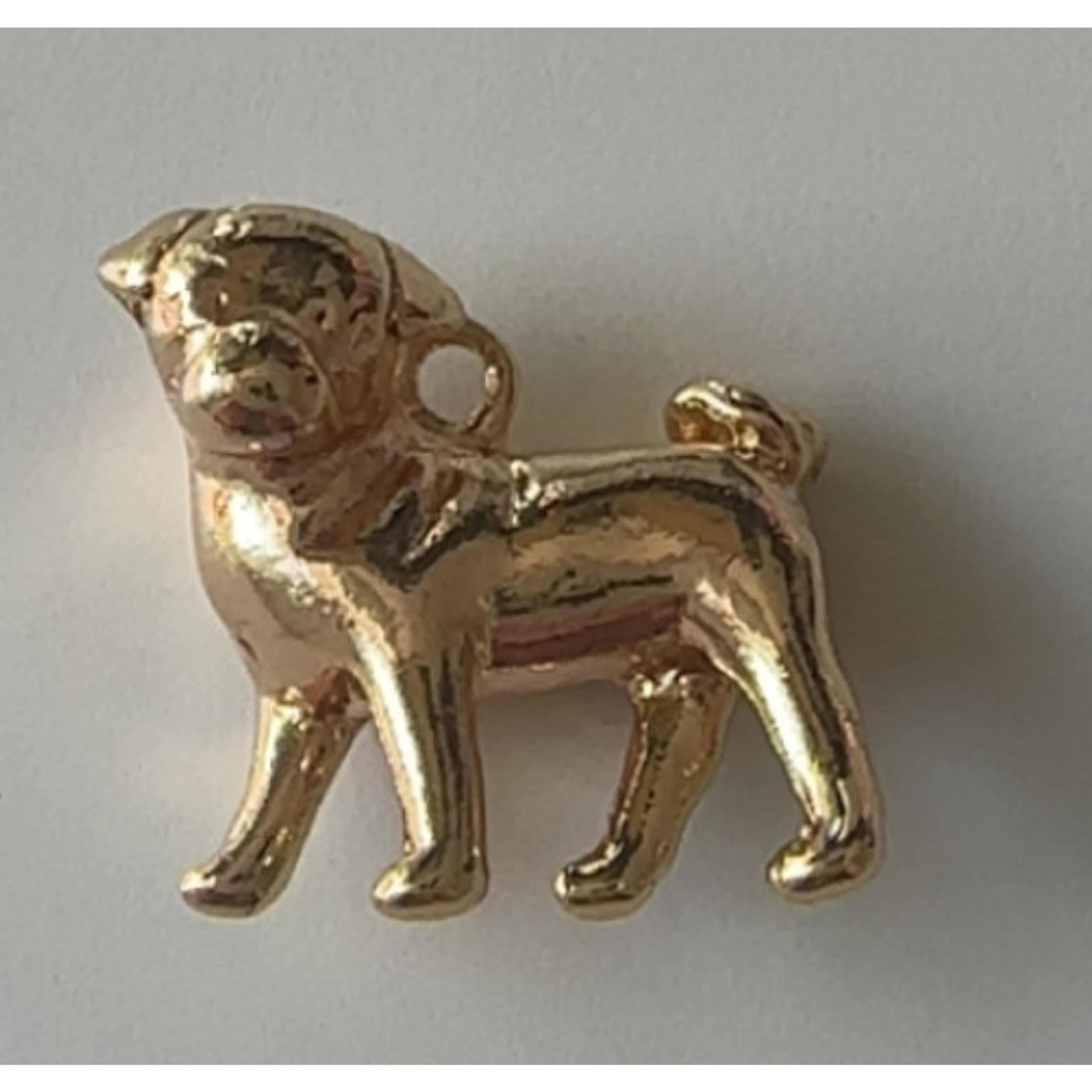Gold dog-shaped charm on a light gray background