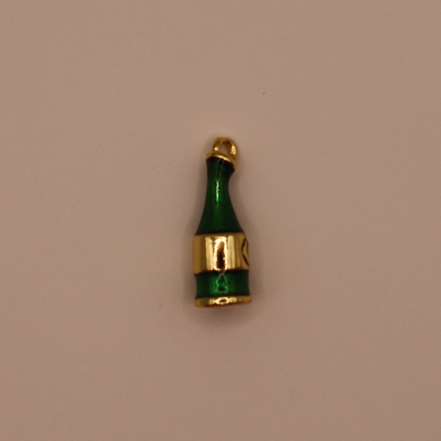 Green champagne bottle-shaped charm with gold accents on a beige background