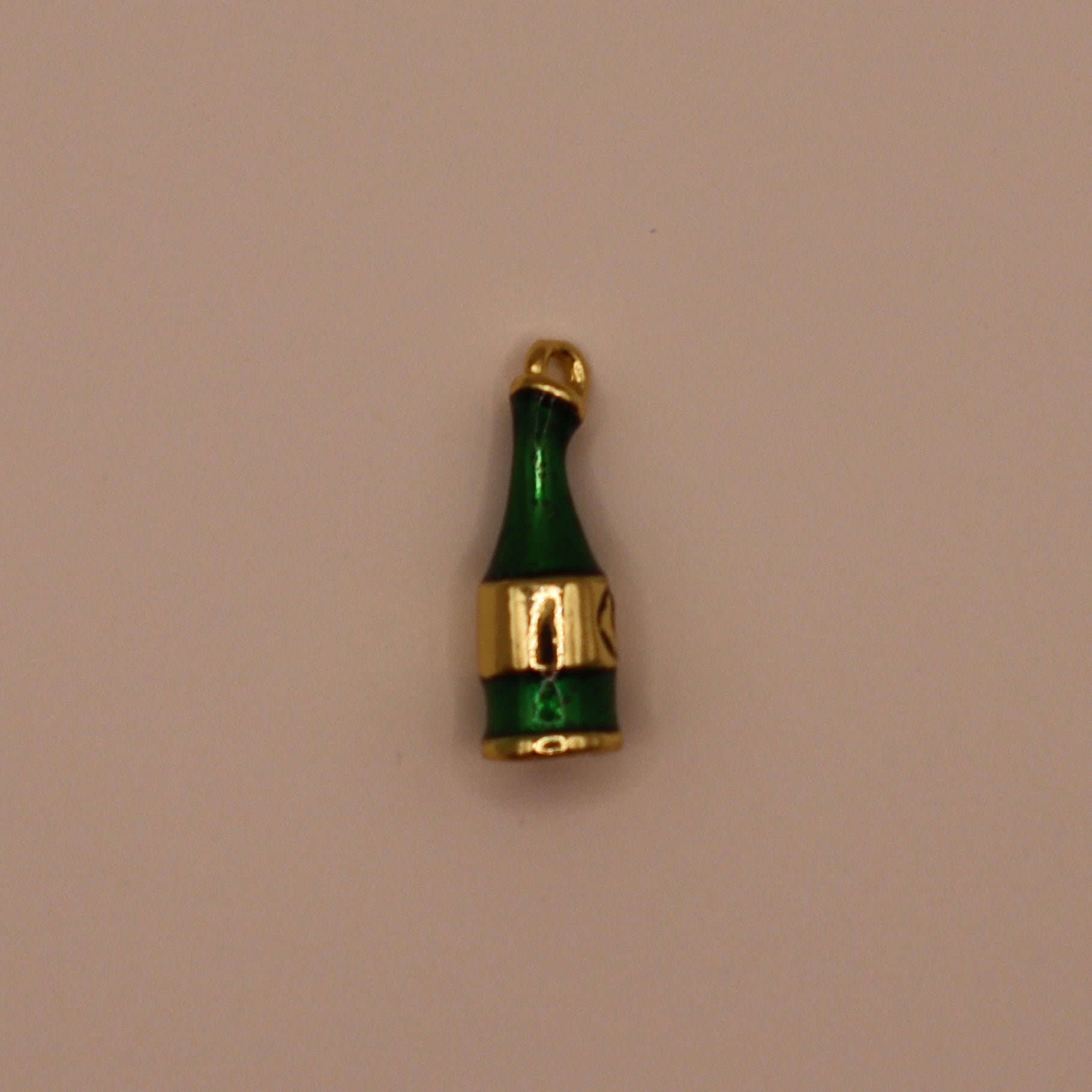 Green champagne bottle-shaped charm with gold accents on a beige background