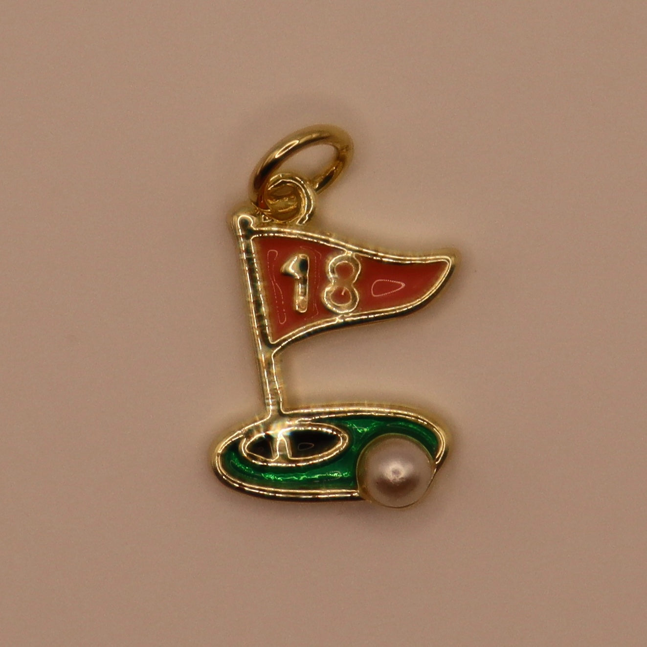 Gold charm resembling a golf flag with number 18 on a beige background