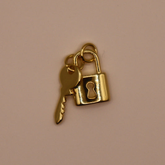 Gold key and lock charm on a beige background