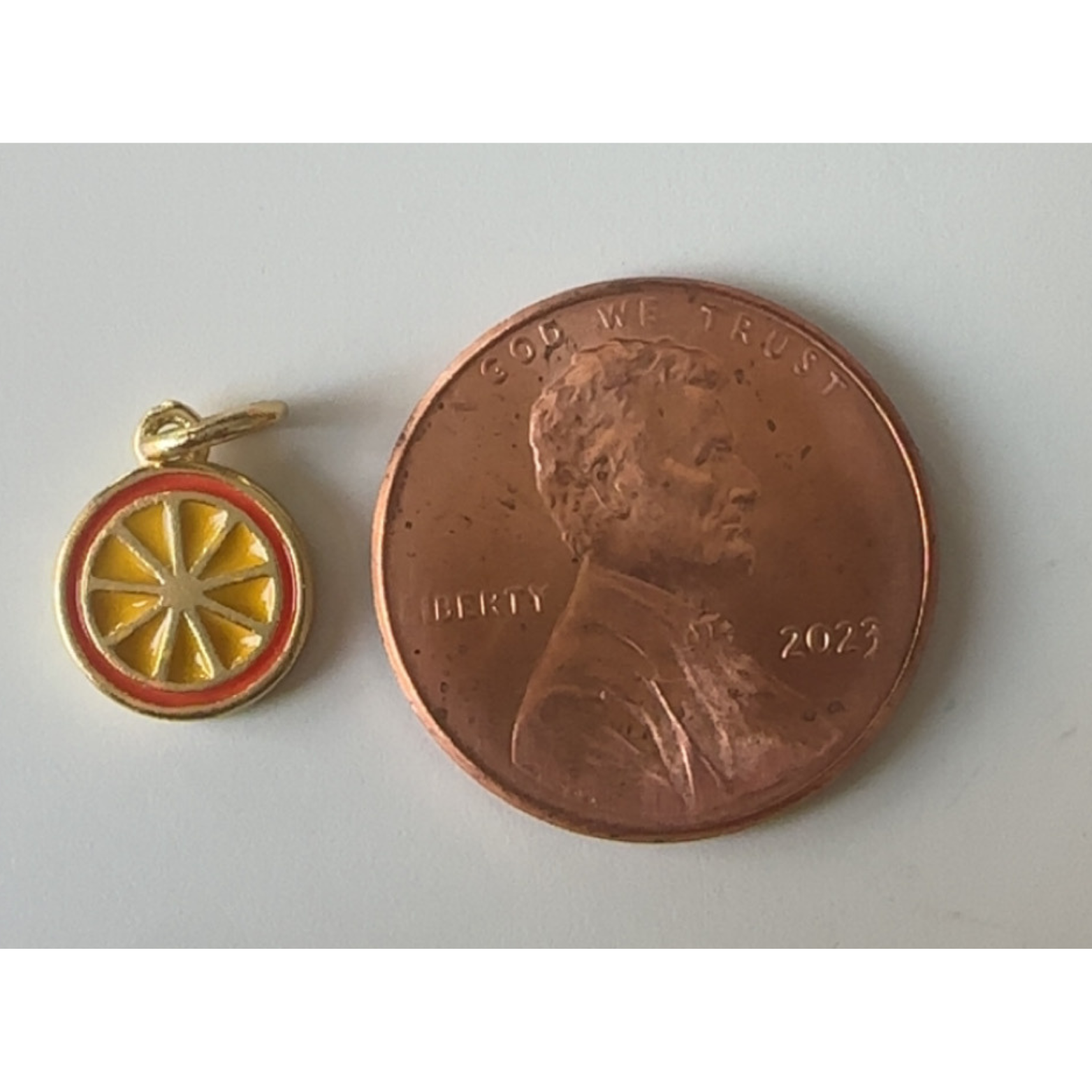 Small orange fruit next to a penny on a light gray background