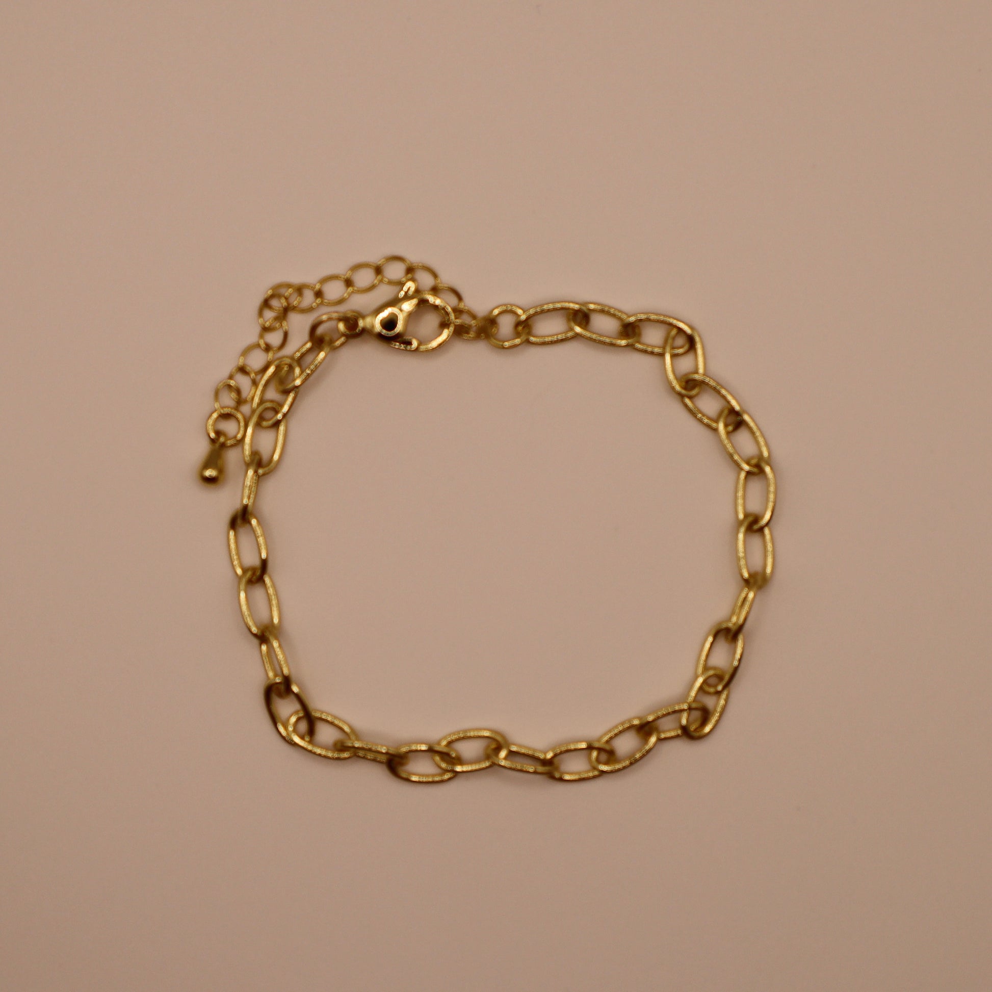 Gold oval bracelet on a beige background
