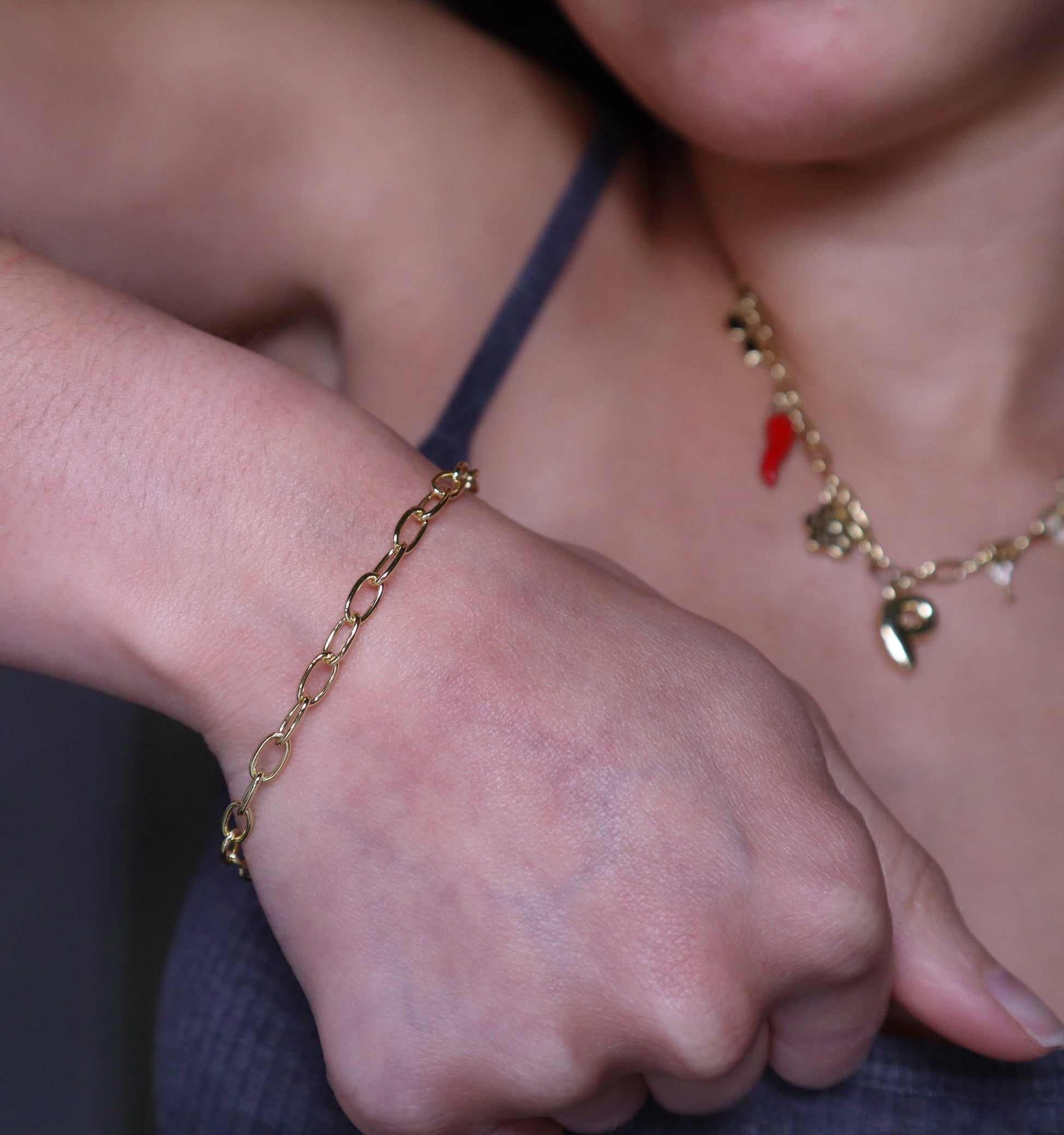 Close-up of a person's wrist wearing a gold oval bracelet with a blurred background