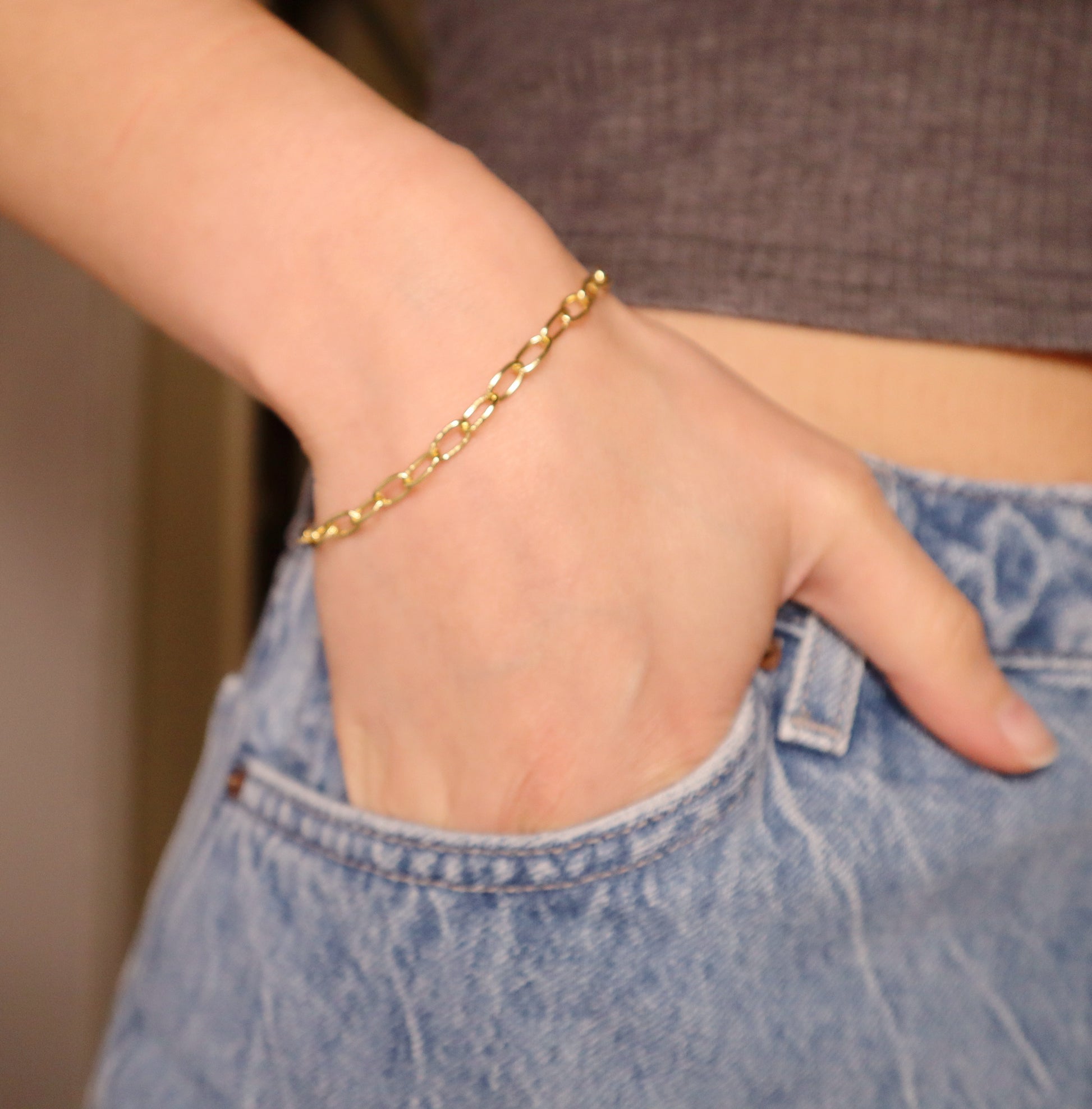 Gold oval bracelet on a wrist with a blurred background
