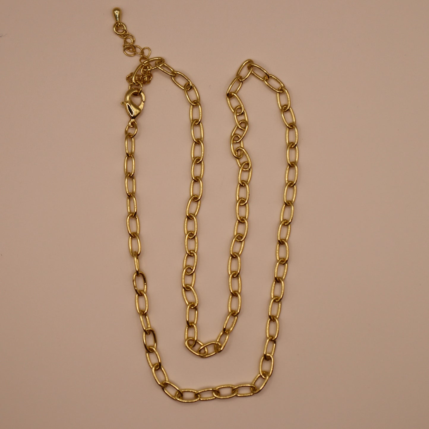 Gold oval necklace on a beige background