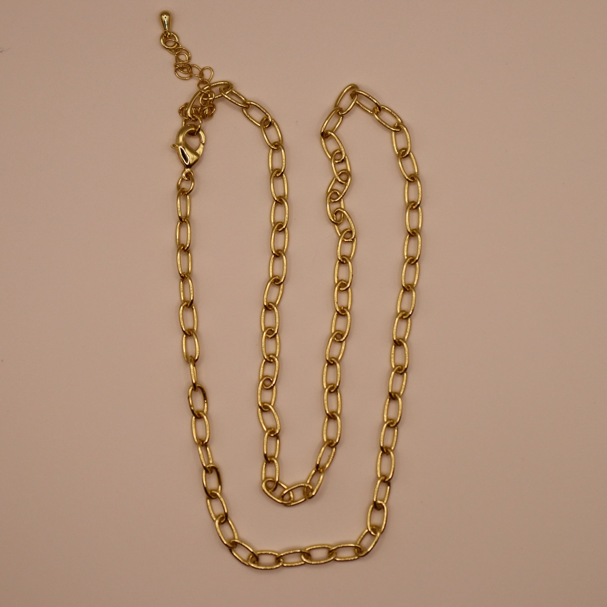 Gold oval necklace on a beige background