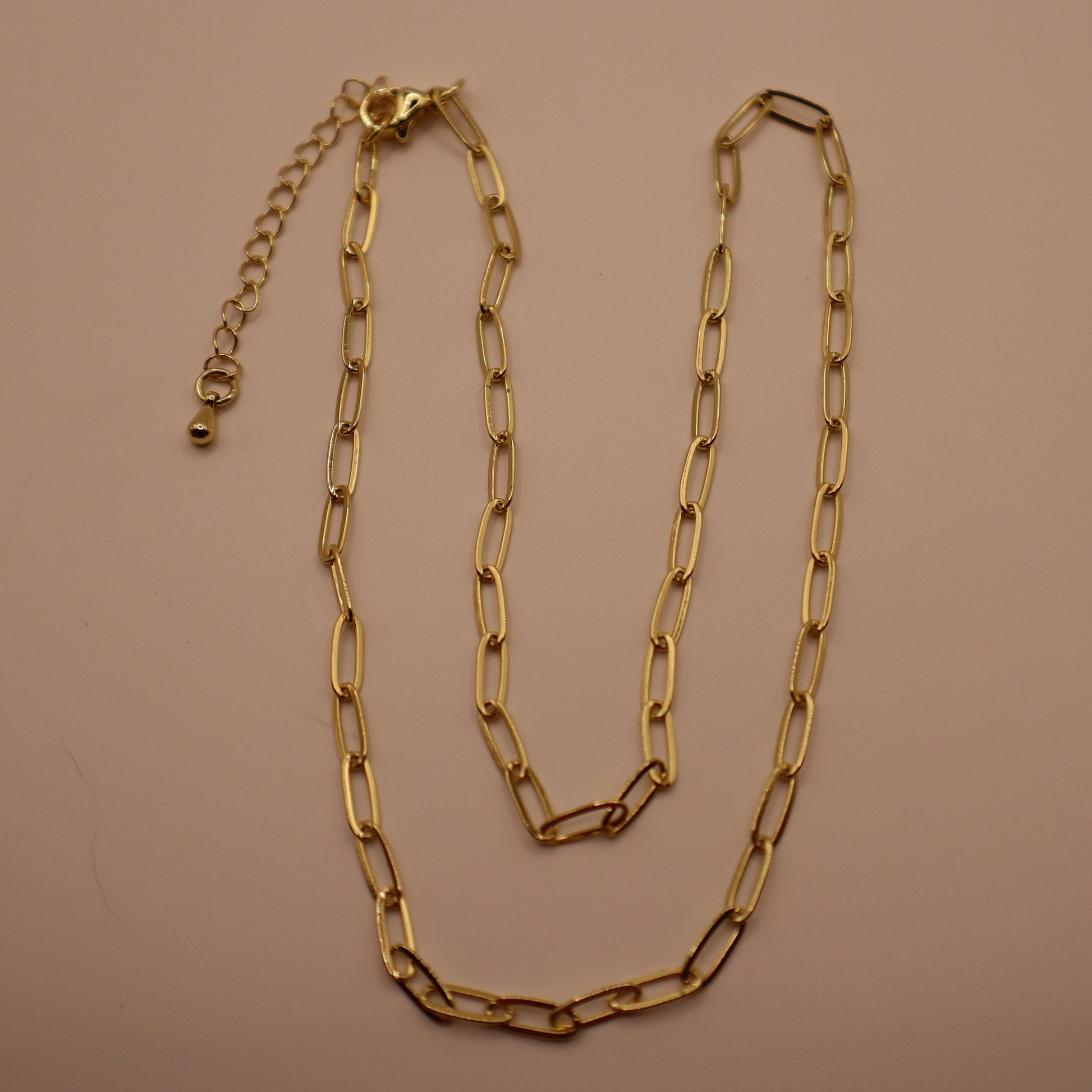 Gold chain necklace on a beige background