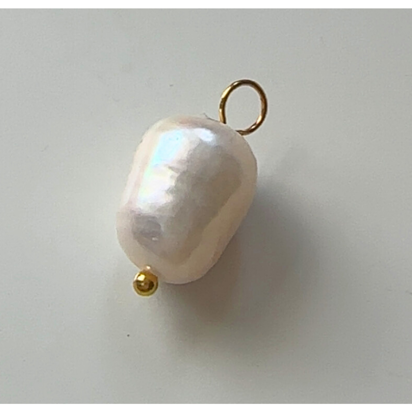 Pearl pendant with gold clasp on a light gray background