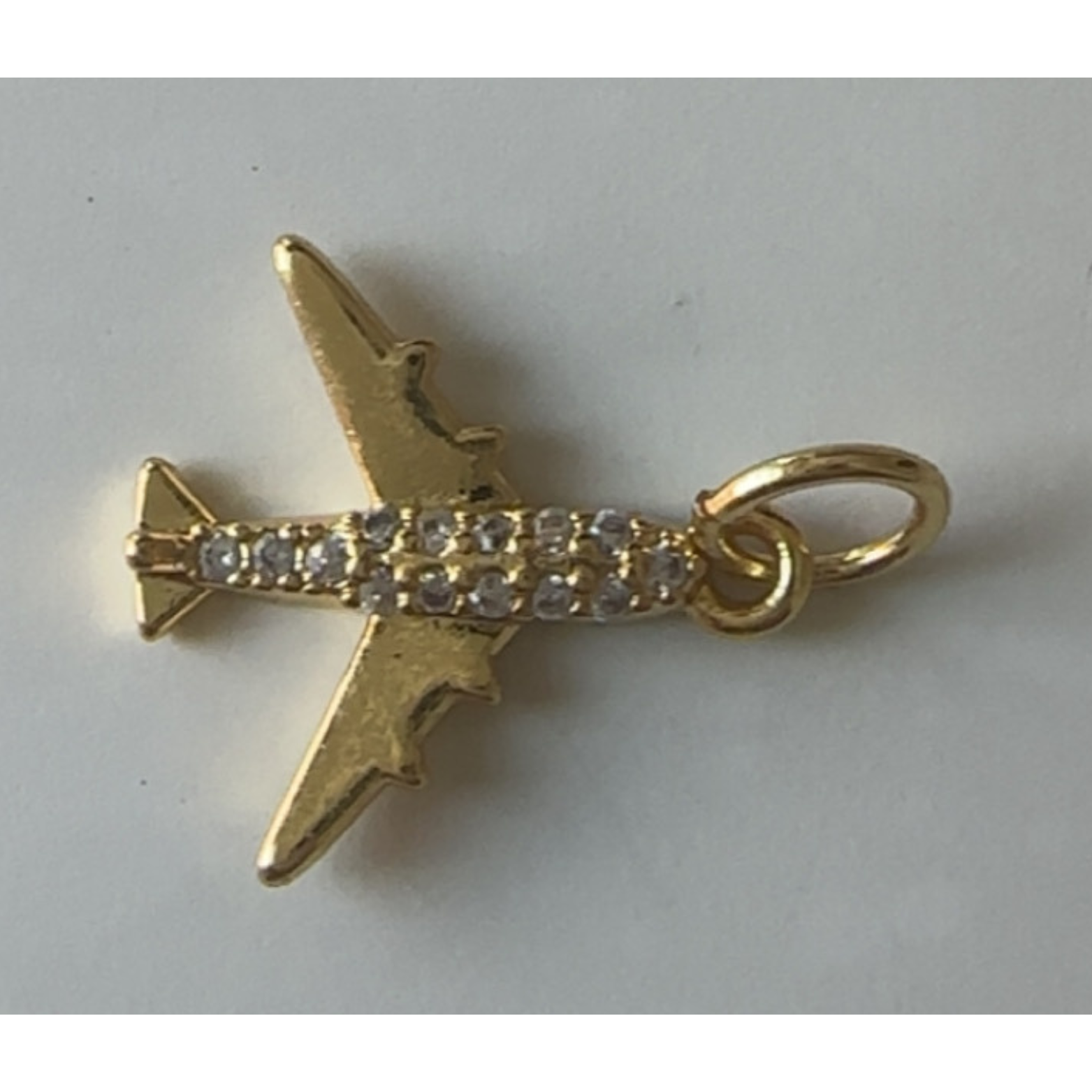 Gold airplane charm with rhinestones on a white background