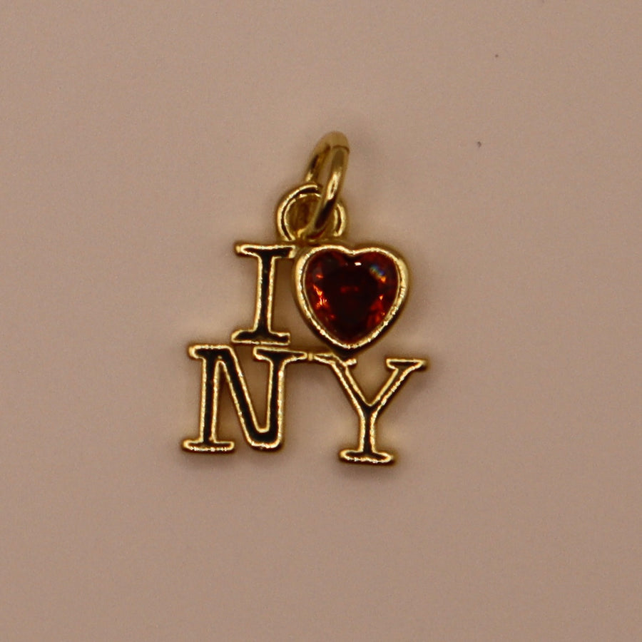 Gold 'I ❤️ NY' pendant with a red heart on a beige background