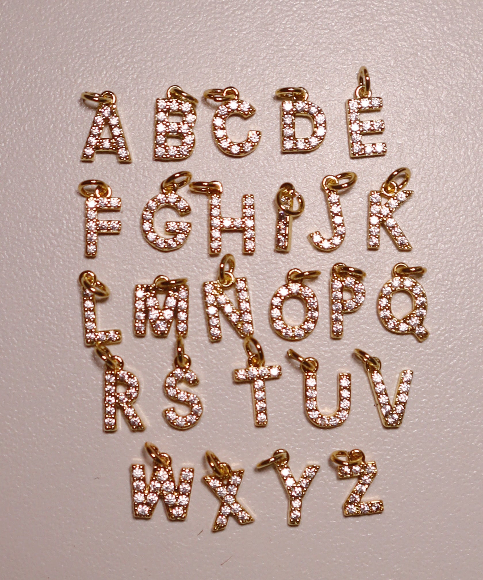 gold letter charms from A to Z on a light gray background