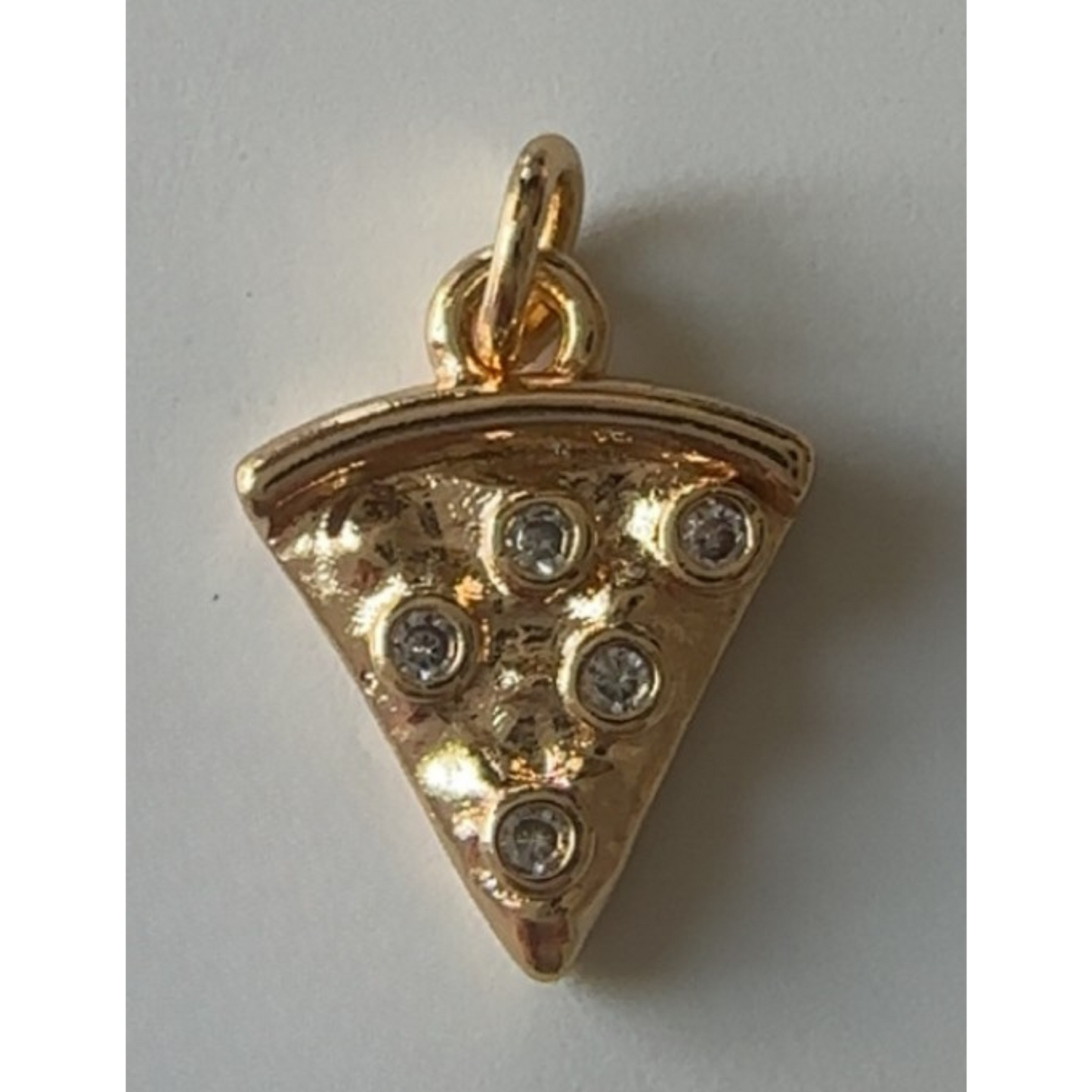 Gold pizza slice pendant with embedded stones on a light gray background