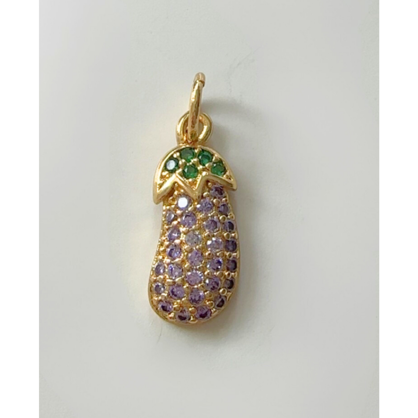 Gold eggplant  pendant with green and purple gemstones on a light gray background