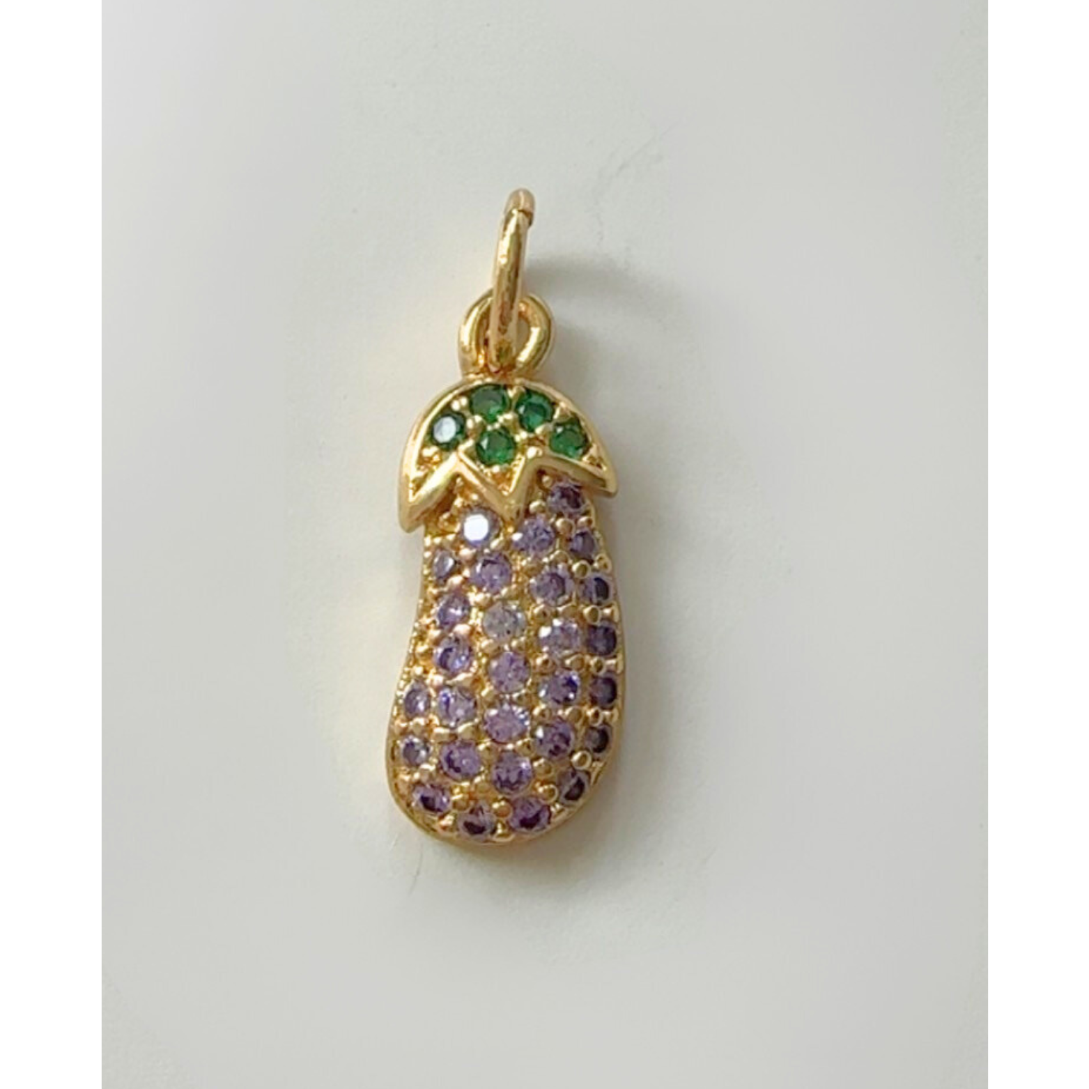 Gold eggplant  pendant with green and purple gemstones on a light gray background