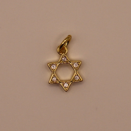 Gold Star of David pendant with embedded stones on a beige background