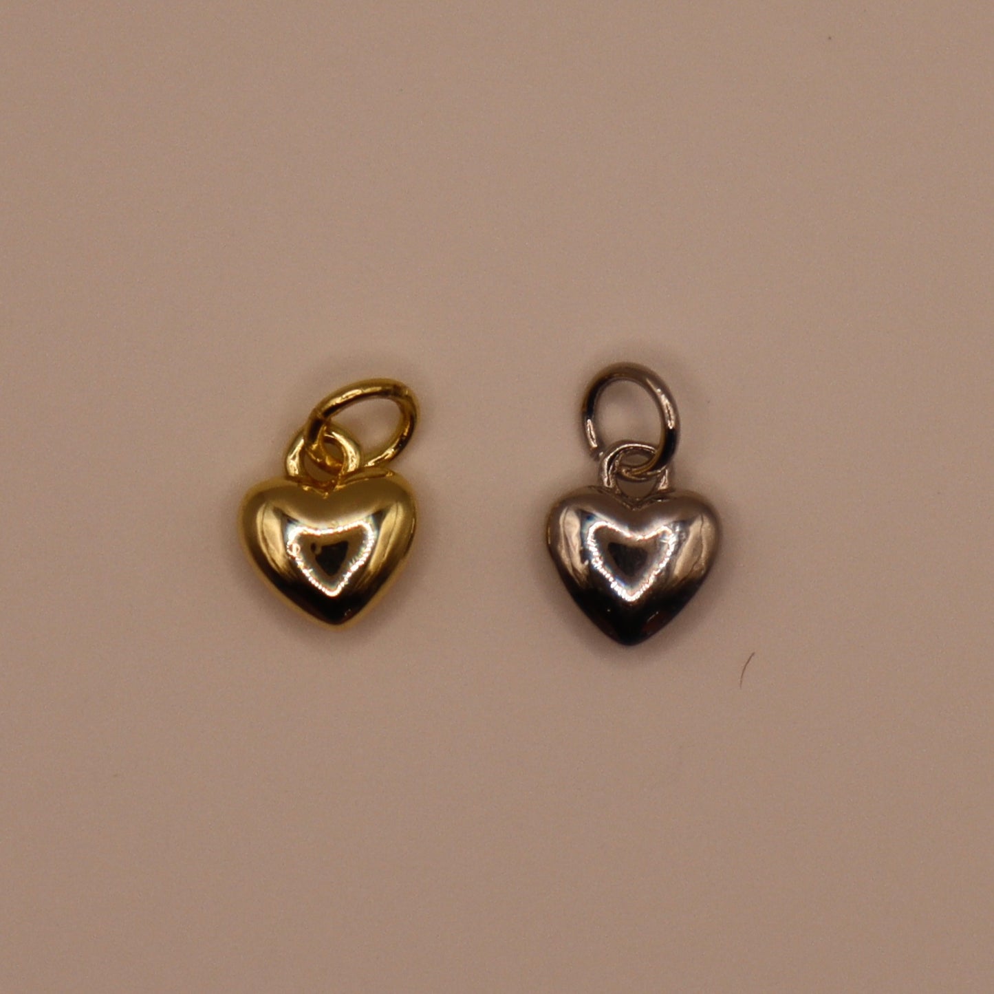 Gold and silver heart-shaped pendants on a beige background