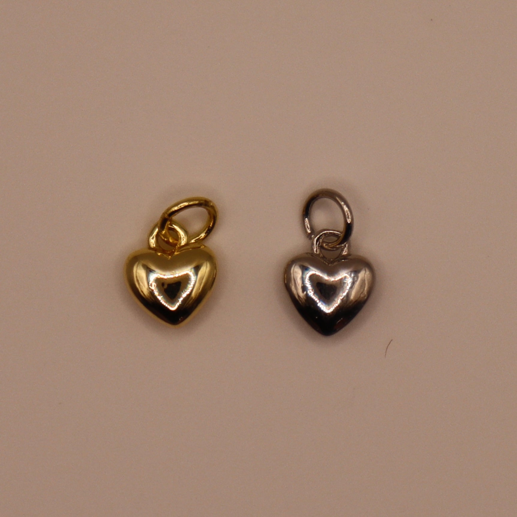 Gold and silver heart-shaped pendants on a beige background